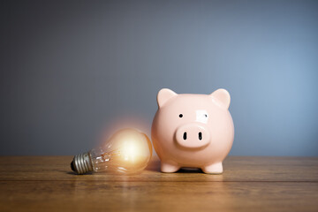 Piggy bank and light bulb on the table