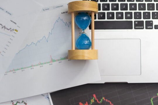 Clock alarm with stock graph chart in laptop screen background.Time,stock market,business success and investment concept.