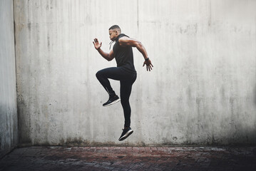 Jump, training and black man running, speed and energy for cardio fitness, workout and sports wellness or body health. Athlete, runner or person exercise on concrete wall, action run or moving in air