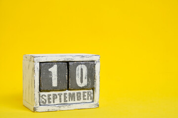 September 10 wooden calendar standing yellow background with an empty space for text.