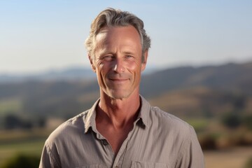 Medium shot portrait photography of a satisfied mature man wearing a casual short-sleeve shirt against a rolling hills background. With generative AI technology