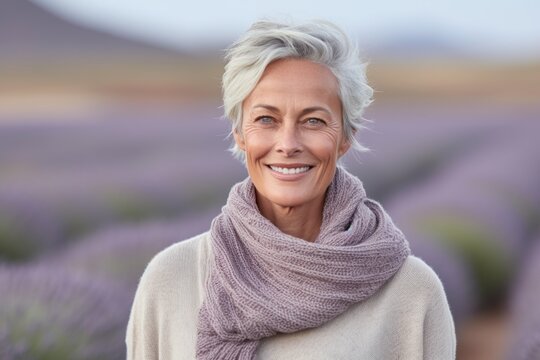 Headshot portrait photography of a satisfied mature woman wearing a cozy sweater against a lavender field background. With generative AI technology