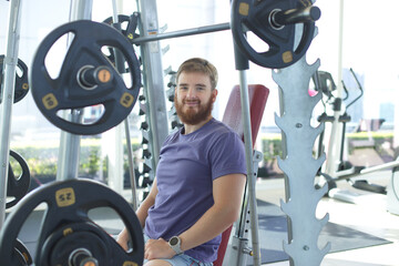 Young happy athletic man is training in the gym doing exercise with barbell