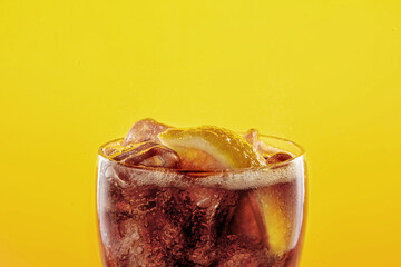 Cola soda glass full of liquid and ice with lemon.