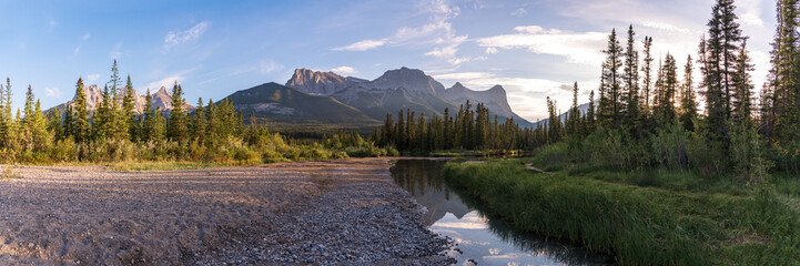 Panoramic view in Canmore, during summertime with huge mountain peaks in view, creek and wilderness...
