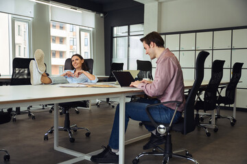 Cheerful female boss daydreaming in presence of her subordinate