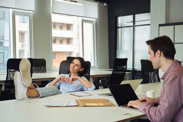 Pleased company manager daydreaming in front of her young assistant