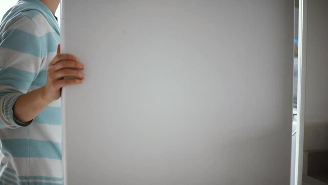 Una mujer camina hasta el refrigerador, se para pensando qu&eacute; tomar y finalmente agarra convencida un tupper con fideos. Gesto de movimiento de dedos mientras decide.