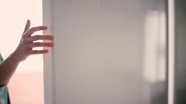Close-up de una mujer caminando hacia el refrigerador, lo abre y saca de &eacute;l una botella de cristal con agua fr&iacute;a.