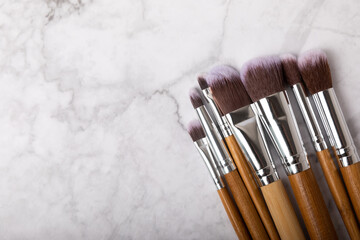 Cosmetic makeup brush on a white marble background. Professional makeup brushes. Eyeshadow, blush, foundation and contouring brushes. Makeup tool. Visagiste. Place for text.Copy space