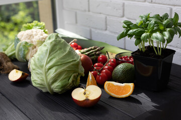 Healthy food concept. Set of fresh vegetables, asparagus, tomatoes, cabbage, cauliflower, green salad, basilica and apples on black wooden background. Front view