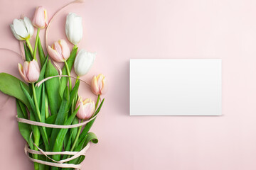 Composition of pink and white tulips, ribbons, blank card on a pink background. Tulips spring bouquet. Content for Birthday, Valentines Day, Womens day. Flat lay, top view, close up, copy space.