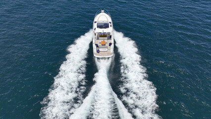 Aerial drone photo of small luxury yacht with wooden deck cruising in high speed deep blue...