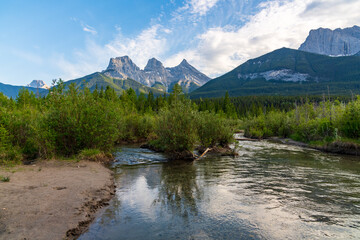 Wilderness, nature view near Banff National Park, Canmore, Three Sisters in summer time. Creek, mountains, forest, woods in scenic, tourism view.