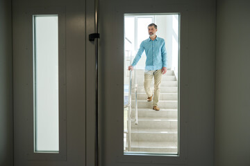 Man with gray beard walks down steps in hospital