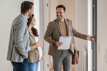 A young couple with a real-estate agent visiting an apartment for sale or for rent. Married couple buying an apartment. Real estate concept. - 611093060