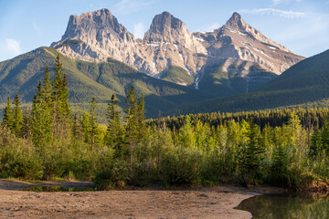 Wilderness area in Canmore with Three Sisters in the background on blue sky day. Stunning area near Banff National Park in popular, tourist, tourism spot for travelling.