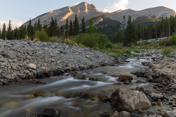 Wilderness creek, stream in Kananaskis, near Banff National Park with stunning Canadian Rockies mountain peaks in background with nature, summer, road trip, travel, wallpaper