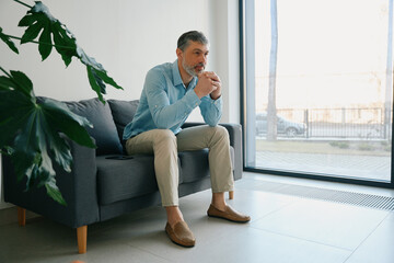 Man leaning on hands sitting on sofa in hospital