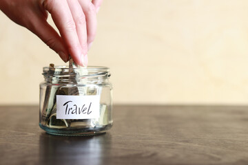 Piggy bank with dollars for travel. Glass jar with money. The woman puts more money in the piggy bank. Selective focus