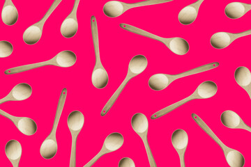 Wooden kitchen spoons scattered randomly on a pink background. Concept of cooking and food preparation	