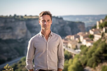 Fototapeta na wymiar Headshot portrait photography of a glad boy in his 30s wearing an elegant long-sleeve shirt against a scenic cliffside village background. With generative AI technology