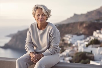Naklejka na ściany i meble Medium shot portrait photography of a glad mature woman wearing soft sweatpants against a scenic cliffside village background. With generative AI technology