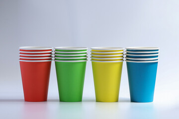 Set of colorful Disposable paper cups isolated on white table top. Glasses of different colors close up. Party utensils for joyful fun different drinks.