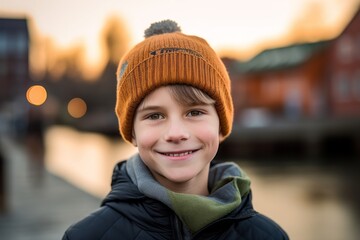 Headshot portrait photography of a grinning kid male wearing a warm beanie or knit hat against a picturesque old town background. With generative AI technology
