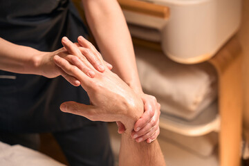 Experienced spa salon masseuse giving hand massage to customer