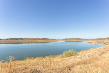 Obraz premium View of swamp. The water level is somewhat low due to lack of rain. Meadow is dry and yellowish. Alange, Extremadura, Spain.
