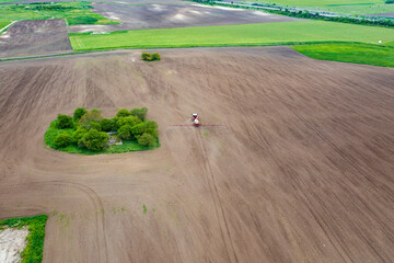 Aerial view of tractor spraying aerosol on a grain fields