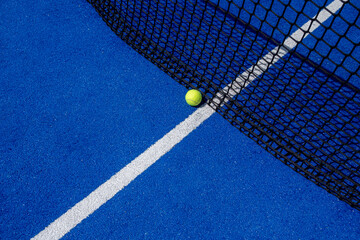 ball close to the net on a blue paddle tennis court