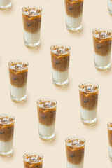 Pattern made from iced latte coffee in glass on beige background. Summer fresh coffe drink