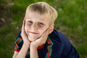 Portrait of a little boy in a blue t-shirt posing in a summer park