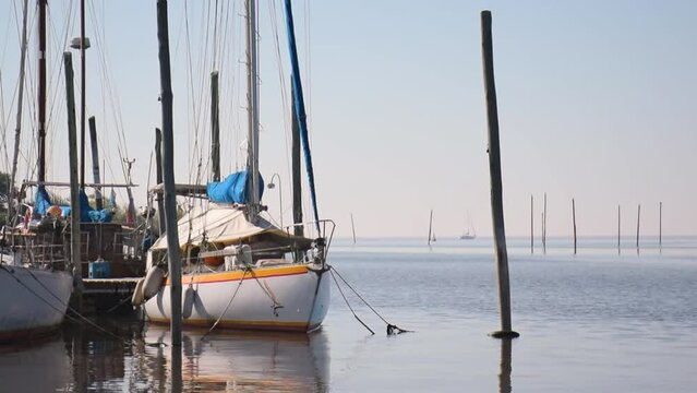 Velero flotando en la bahia. Barco atracado en el puerto maritimo. Reflejo del bote sobre el agua.