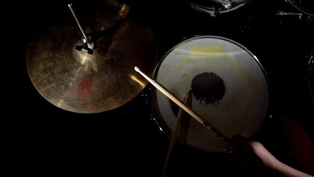 Professional musician drummer is playing on drum kit hitting drum and cymbals.