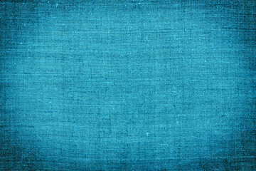 Blue linen fabric with light center and vignette for background or texture, top view, close-up