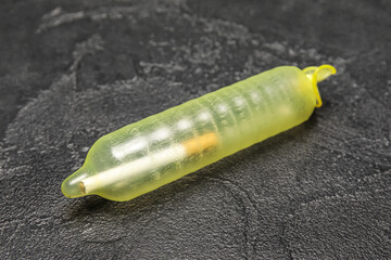 Inflated condom with cigarette inside on dark background. Stop smoking concept