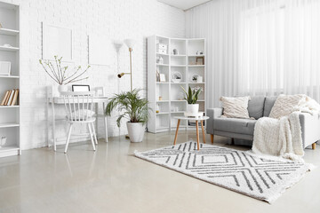 Stylish interior of light living room with modern laptop on table