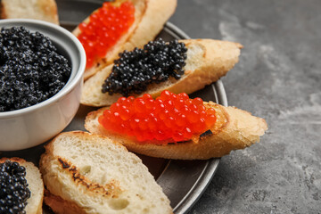 Tasty bruschettas with red and black caviar on dark grunge background