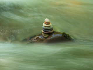 Zen stones in the flow of the river, concept of balance in chaos