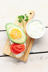 Board of tasty bruschetta with avocado and cream cheese on light wooden background