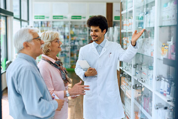 Fototapeta na wymiar Young Muslim pharmacist assists senior couple in choosing products in drugstore.