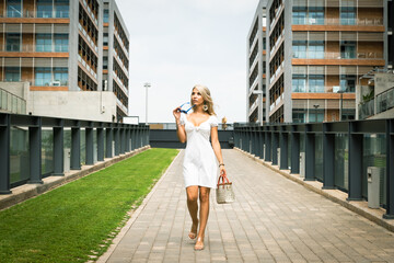PRETTY BLONDE GIRL WALKING WITH GLASSES AND A BAG IN HER HAND