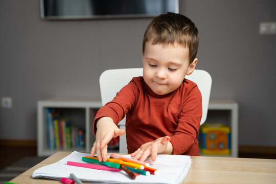 A cute little toddler boy of two years old draws with markers in the album in the children's room at home. Educational activities for kids. Selective focus