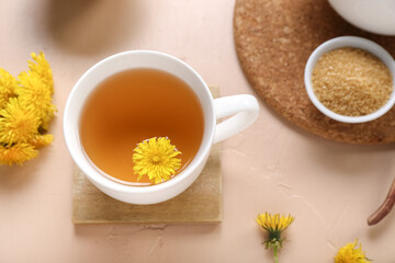 Cup of healthy dandelion tea on beige background
