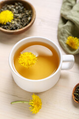 Bowl and cup of healthy dandelion tea on white wooden background