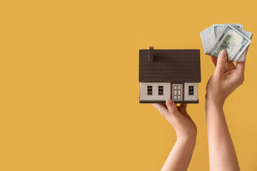 Fototapeta na wymiar Woman with money and house model on yellow background