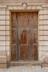 original wooden medieval door in sandstone facade of a historical building on mediterranean island